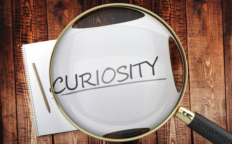 A magnifying glass highlighted a paper with the word "curiosity" on it