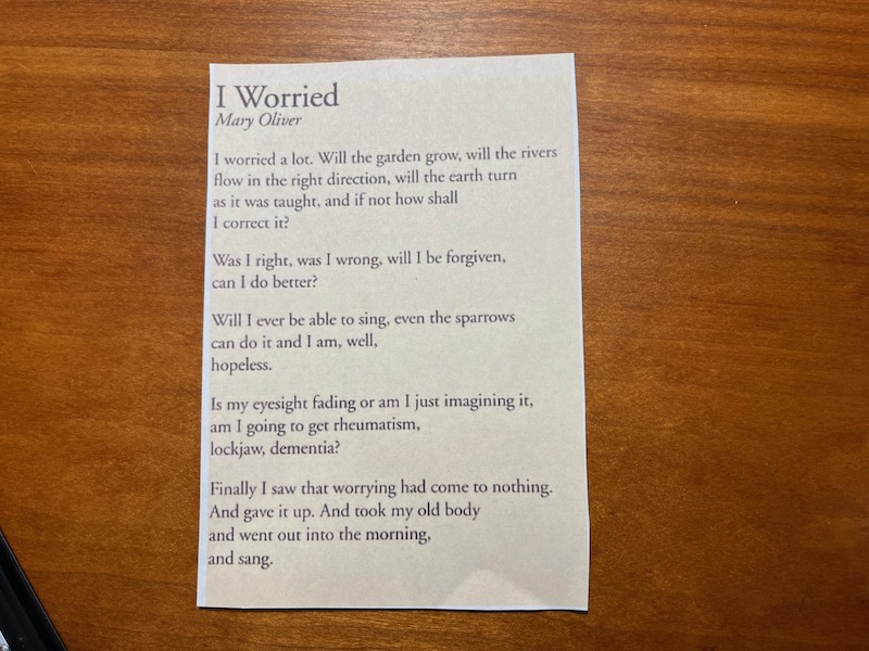 A poem by Mary Oliver taped to a wood shelf