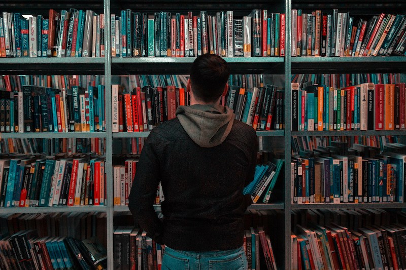 The back of a man looking at shelves in a public library