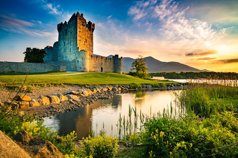 Kilkenny Castle in Ireland surrounded by lush fields and a meandering stream