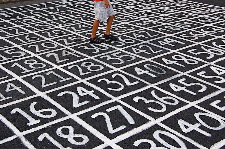 A person is stepping from one number to another on a ground covered in numbered rectangles
