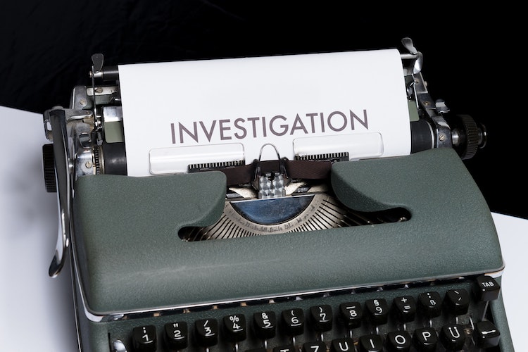 photo typewriter with paper in carriage that says "investigation"