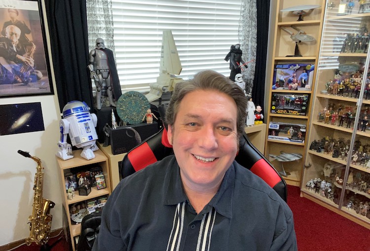 Photo of Bryan Mendez in his home office filled with Star Trek and Star Wars memorabilia